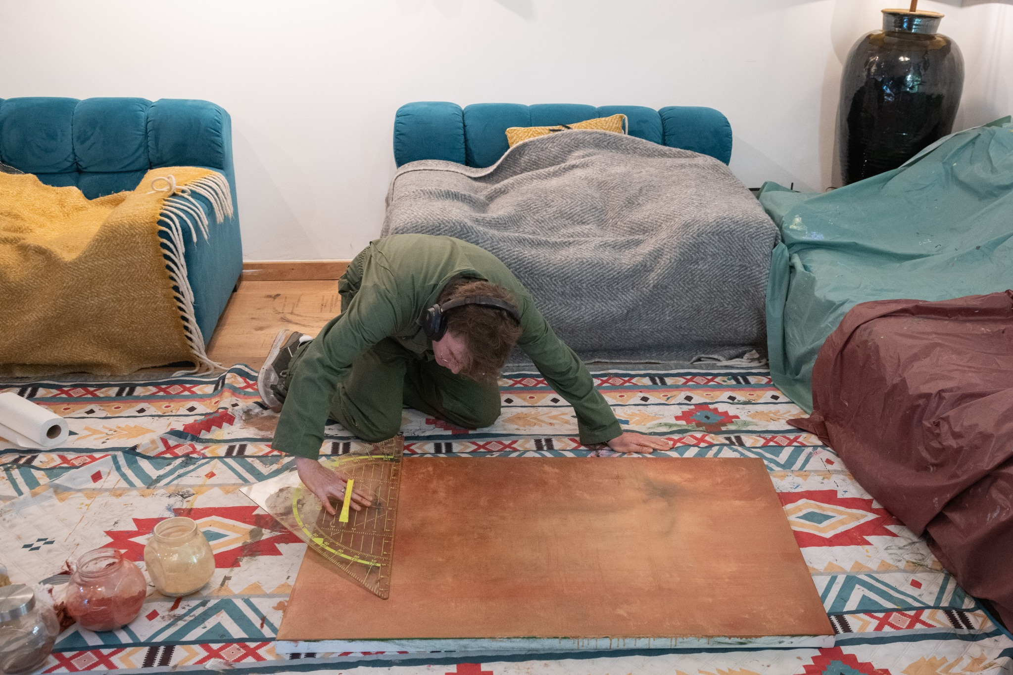 Ward Schepman, wearing headphones, drawing lines on a canvas with a triangular ruler and pencil.